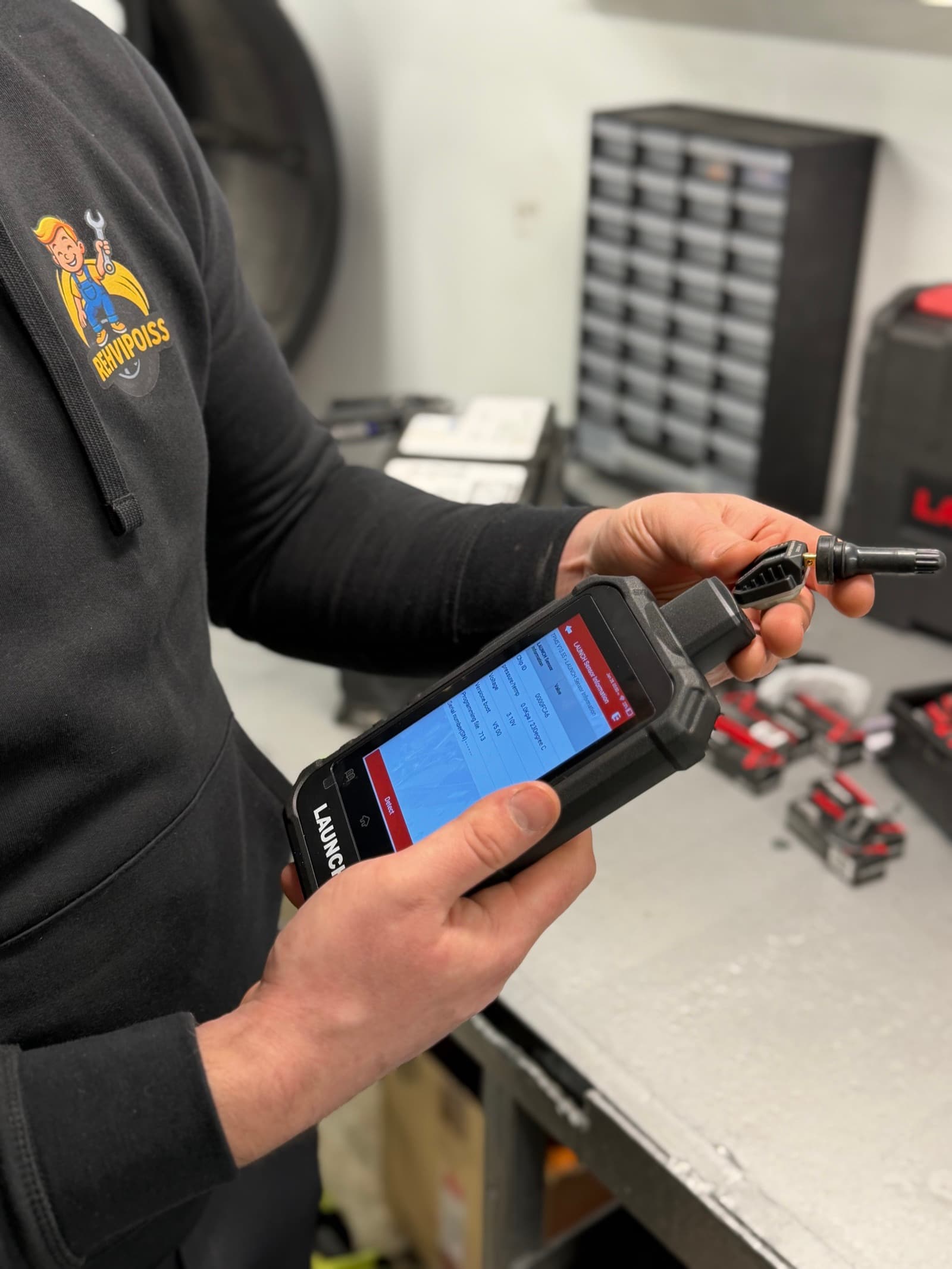 A Rehvipoiss technician checking TPMS sensor data with a LAUNCH device
